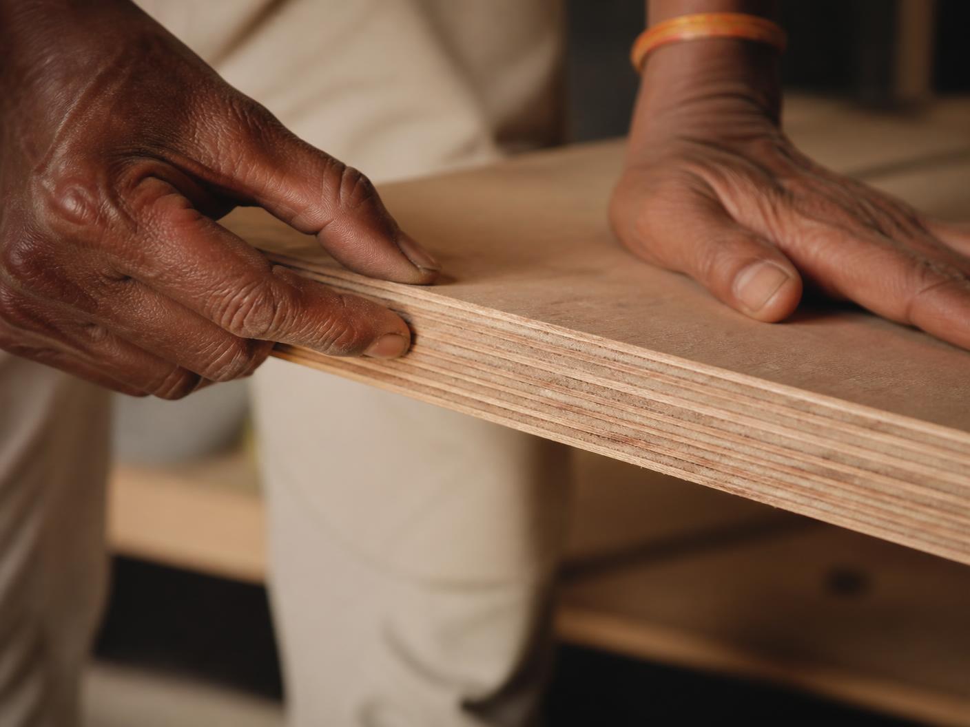 Hands running along the cut edge of a plywood sheet