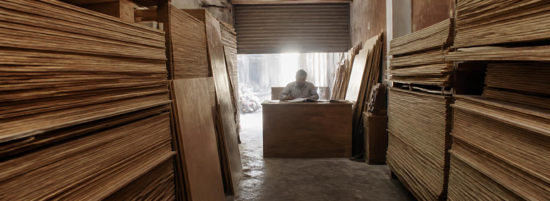 Wide view down the aisle of a plywood godown towards the counter